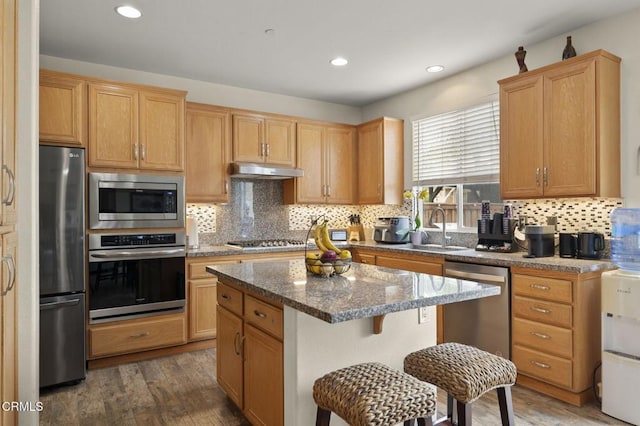 371 Huerta St, Oxnard, CA 93030 - kitchen featuring stainless steel appliances, dark wood finished floors, backsplash, a kitchen island, and under cabinet range hood