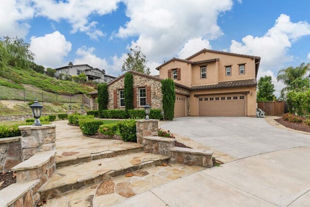 6851 Helenite Pl, Carlsbad, CA 92009 - mediterranean / spanish-style house with stucco siding, an attached garage, driveway, a tile roof, and stone siding