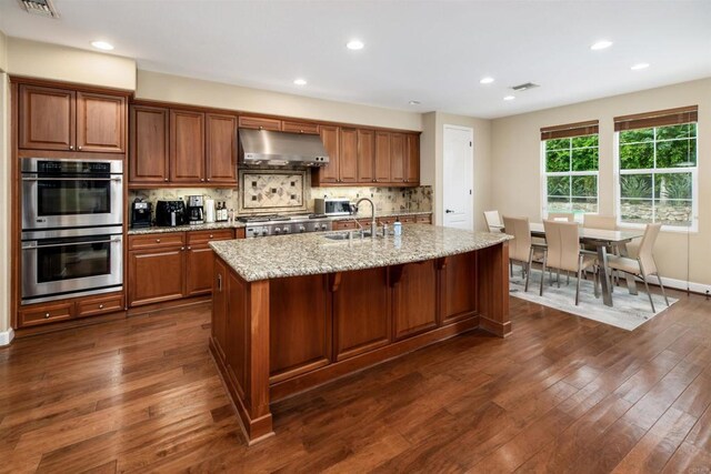 6851 Helenite Pl, Carlsbad, CA 92009 - kitchen with range hood, stainless steel double oven, brown cabinetry, dark wood-type flooring, and a sink