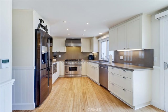 34155 Calle Ln, Primavera, Dana Point, CA 92629 - kitchen with stainless steel appliances, wall chimney exhaust hood, a sink, light wood finished floors, and white cabinetry