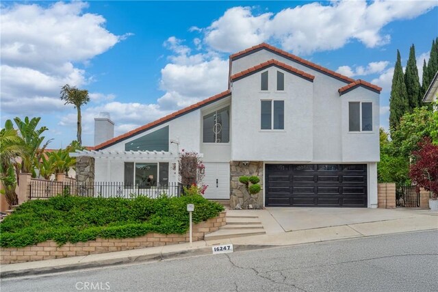 16247 Elza Dr, Hacienda Heights, CA 91745 - mediterranean / spanish house featuring stone siding, an attached garage, concrete driveway, stucco siding, and a chimney