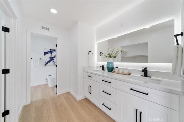 16247 Elza Dr, Hacienda Heights, CA 91745 - full bathroom with double vanity, toilet, wood finished floors, and baseboards