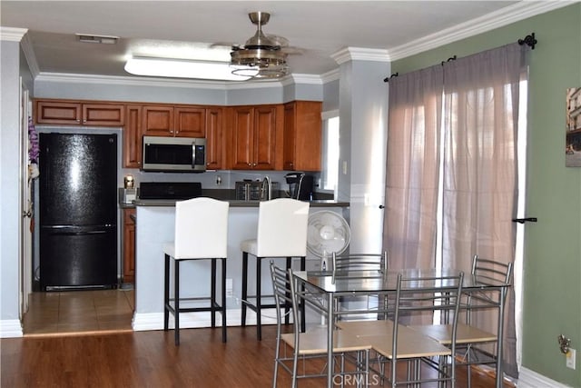 920 Nettle Ct, Corona, CA 92878 - kitchen with freestanding refrigerator, stainless steel microwave, brown cabinets, crown molding, and range