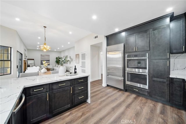 2545 Scenic Ridge Dr, Chino Hills, CA 91709 - kitchen with appliances with stainless steel finishes, open floor plan, light wood-style floors, light stone counters, and dark cabinetry