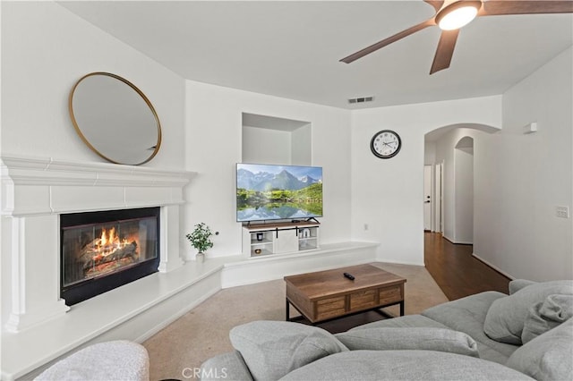 27625 Mariposa Ln, Castaic, CA 91384 - living room featuring arched walkways, a ceiling fan, a glass covered fireplace, and carpet floors