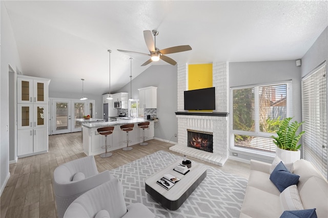 2712 Boundary Ln, Riverside, CA 92503 - living room with vaulted ceiling, a ceiling fan, a fireplace, light wood finished floors, and baseboards