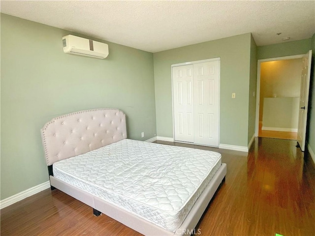 3855 Gilman Rd, El Monte, CA 91732 - bedroom featuring a wall mounted AC, wood finished floors, a closet, baseboards, and a textured ceiling