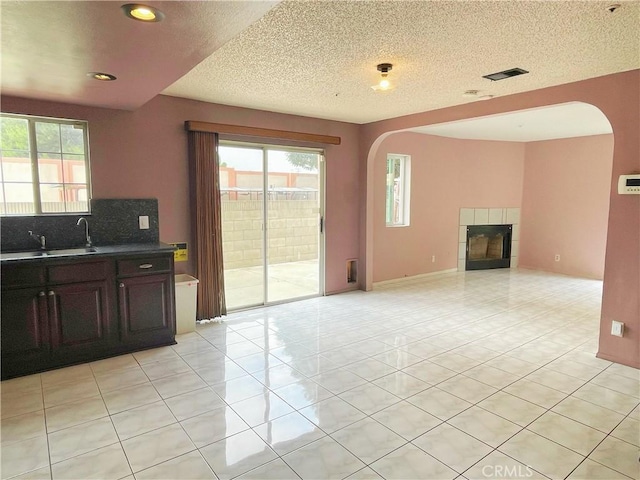 3855 Gilman Rd, El Monte, CA 91732 - kitchen featuring arched walkways, plenty of natural light, decorative backsplash, a fireplace, and a textured ceiling