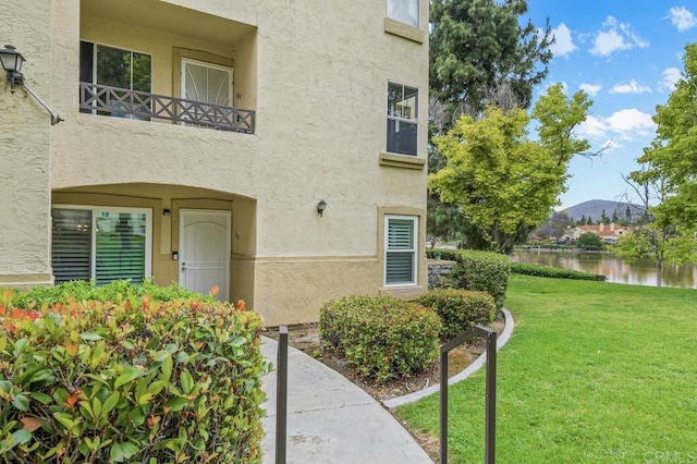 783 Brookstone Rd Unit 104, Chula Vista, CA 91913 - view of exterior entry with stucco siding, a water and mountain view, and a yard