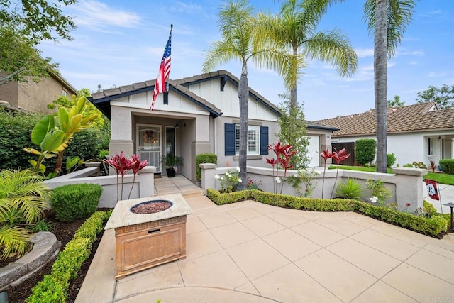 1064 Eliot St, Oceanside, CA 92057 - view of front facade with a garage, board and batten siding, an outdoor fire pit, and stucco siding