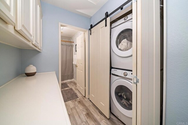 1064 Eliot St, Oceanside, CA 92057 - laundry area with stacked washer / drying machine, a barn door, and light wood-style flooring