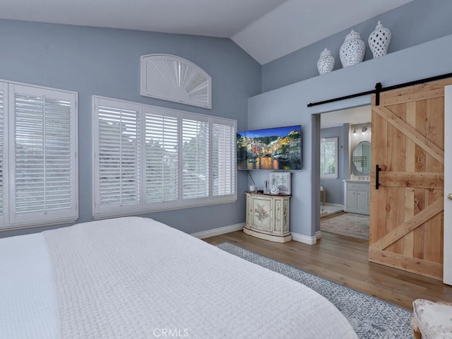 28 Covington, Mission Viejo, CA 92692 - bedroom with a barn door, wood finished floors, ensuite bathroom, and high vaulted ceiling
