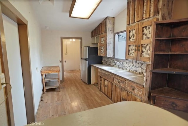 44037 Heaton Ave, Lancaster, CA 93534 - kitchen featuring light wood-style flooring, brown cabinetry, freestanding refrigerator, a sink, and backsplash