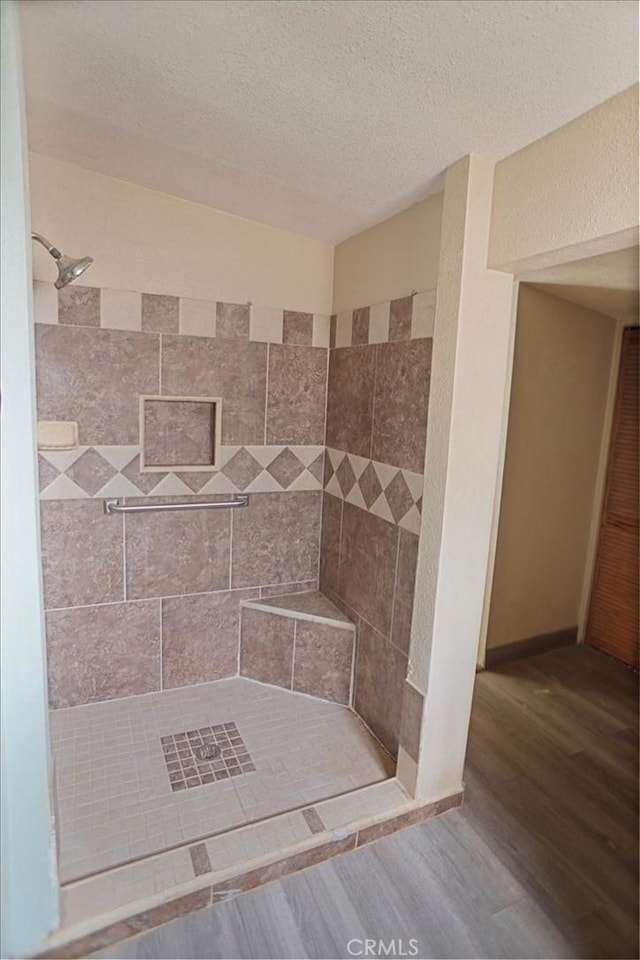 44037 Heaton Ave, Lancaster, CA 93534 - bathroom featuring a tile shower, wood finished floors, and a textured ceiling