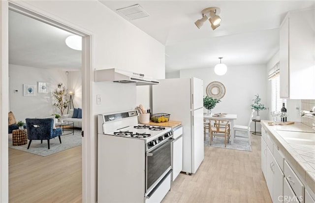 1139 W 149th St, Gardena, CA 90247 - kitchen with white gas range oven, under cabinet range hood, light wood finished floors, white cabinets, and a sink