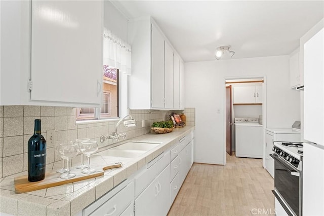 1139 W 149th St, Gardena, CA 90247 - kitchen featuring washer / clothes dryer, white range oven, a sink, white cabinets, and backsplash
