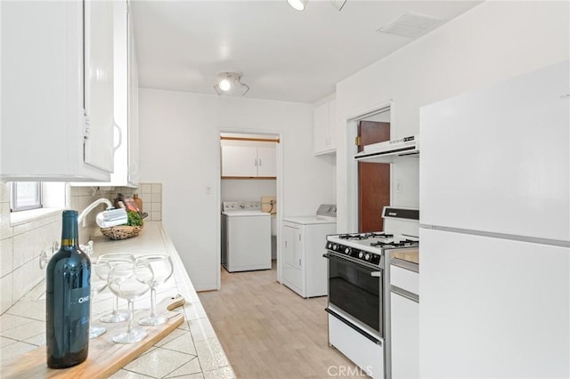 1139 W 149th St, Gardena, CA 90247 - kitchen featuring white appliances, washing machine and clothes dryer, white cabinetry, under cabinet range hood, and light wood-style floors