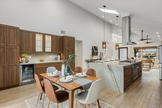3995 Cypress Del Mar, San Diego, CA 92130 - kitchen with wine cooler, island range hood, high vaulted ceiling, stainless steel appliances, and light wood-type flooring