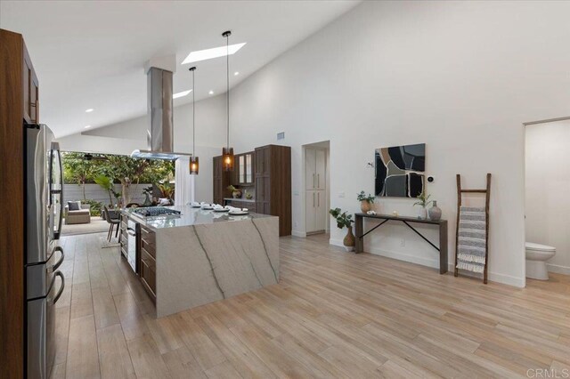 3995 Cypress Del Mar, San Diego, CA 92130 - kitchen with island range hood, stainless steel appliances, light stone countertops, light wood-style floors, and a skylight