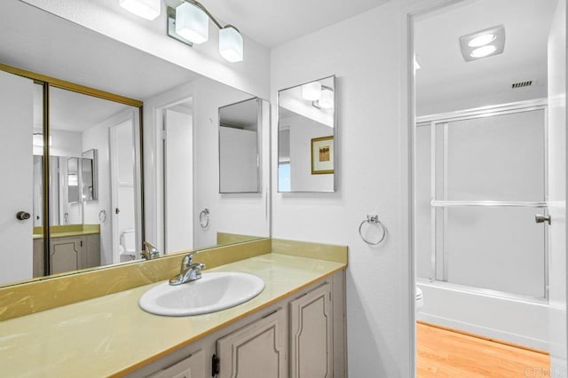 3635 7th Ave Unit 13E, San Diego, CA 92103 - bathroom featuring toilet, vanity, combined bath / shower with glass door, and wood finished floors