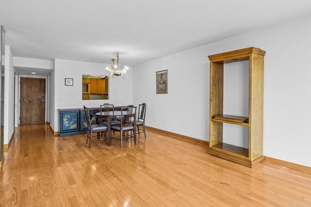 3635 7th Ave Unit 13E, San Diego, CA 92103 - dining area featuring a chandelier, wood finished floors, and baseboards