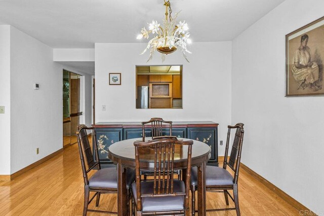 3635 7th Ave Unit 13E, San Diego, CA 92103 - dining space featuring light wood finished floors, a chandelier, and baseboards