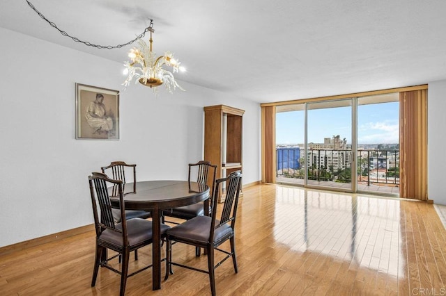 3635 7th Ave Unit 13E, San Diego, CA 92103 - dining space with a chandelier, light wood-style floors, expansive windows, and baseboards