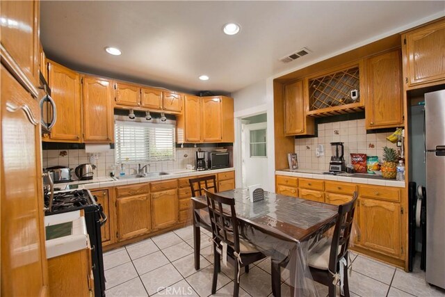 2756 W 15th St, Los Angeles, CA 90006 - kitchen with gas range, decorative backsplash, tile countertops, light tile patterned floors, and recessed lighting
