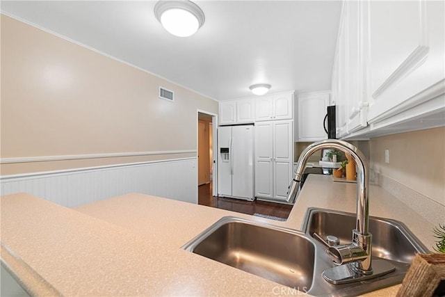 12670 Oxford Dr, La Mirada, CA 90638 - kitchen with white refrigerator with ice dispenser, a sink, white cabinets, a wainscoted wall, and light countertops