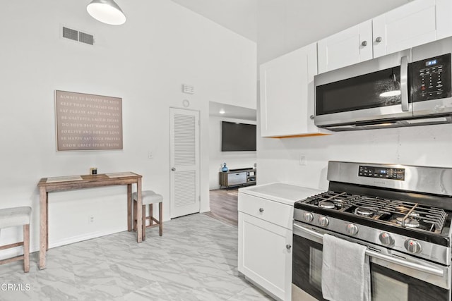5321 Colodny Dr Unit 4, Agoura Hills, CA 91301 - kitchen with appliances with stainless steel finishes, light marble finish floors, white cabinetry, a towering ceiling, and light countertops