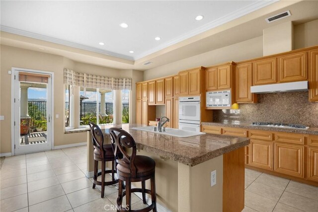 20130 Thagard Way, Yorba Linda, CA 92887 - kitchen with white appliances, under cabinet range hood, light tile patterned floors, an island with sink, and crown molding