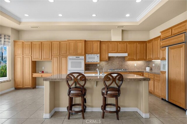 20130 Thagard Way, Yorba Linda, CA 92887 - kitchen featuring built in appliances, crown molding, a kitchen island with sink, decorative backsplash, and light tile patterned floors