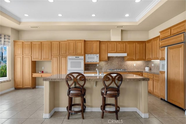 20130 Thagard Way, Yorba Linda, CA 92887 - kitchen featuring built in appliances, ornamental molding, a center island with sink, decorative backsplash, and light tile patterned flooring