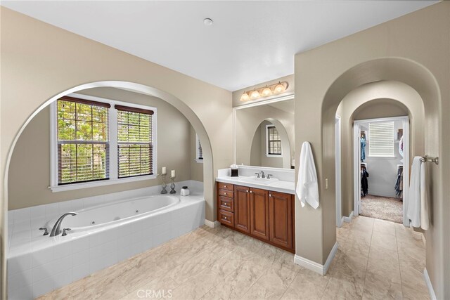 7 Illuminata Ln, Ladera Ranch, CA 92694 - bathroom with vanity, a whirlpool tub, marble look tiles, and baseboards