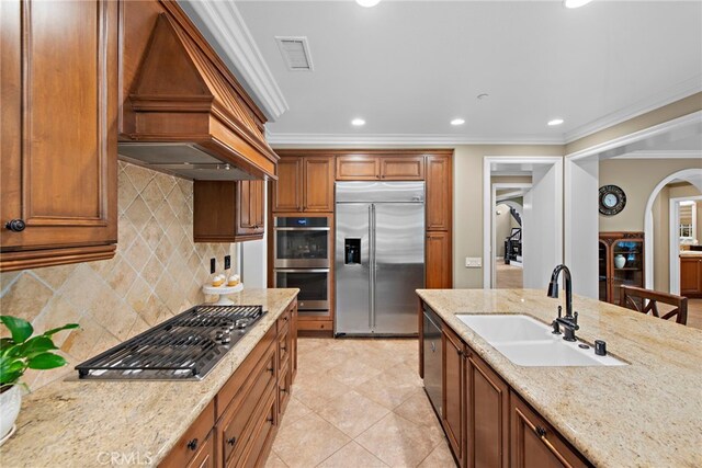 7 Illuminata Ln, Ladera Ranch, CA 92694 - kitchen with appliances with stainless steel finishes, a sink, premium range hood, arched walkways, and ornamental molding