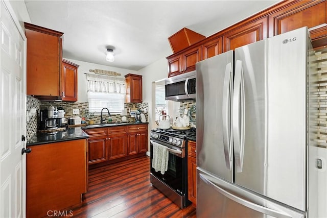 210 W Tichenor St, Compton, CA 90220 - kitchen with appliances with stainless steel finishes, dark countertops, a sink, dark wood-style floors, and decorative backsplash