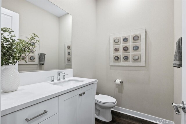 27227 Coyote Bush Ct, Valencia, CA 91381 - half bath with baseboards, vanity, wood finished floors, and toilet