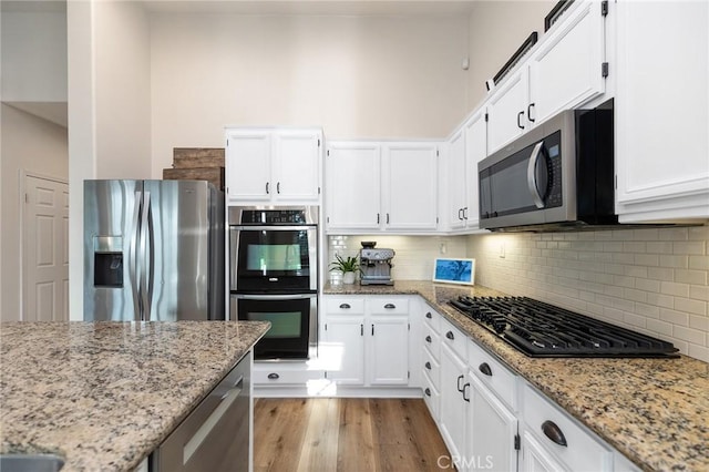 7476 Sequoia Ln, Highland, CA 92346 - kitchen with stainless steel appliances, white cabinets, light stone countertops, tasteful backsplash, and light wood-style floors