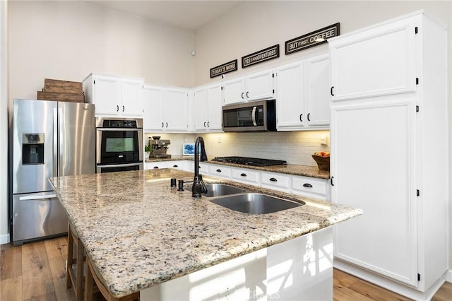7476 Sequoia Ln, Highland, CA 92346 - kitchen featuring stainless steel appliances, light wood-style flooring, white cabinetry, backsplash, and light stone countertops
