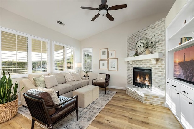 7476 Sequoia Ln, Highland, CA 92346 - living area with vaulted ceiling, a fireplace, a ceiling fan, and light wood-style flooring