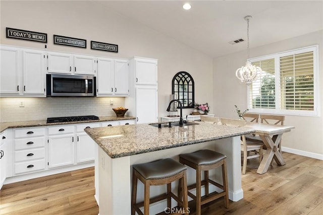 7476 Sequoia Ln, Highland, CA 92346 - kitchen featuring stainless steel microwave, a sink, black gas cooktop, light stone countertops, and white cabinets