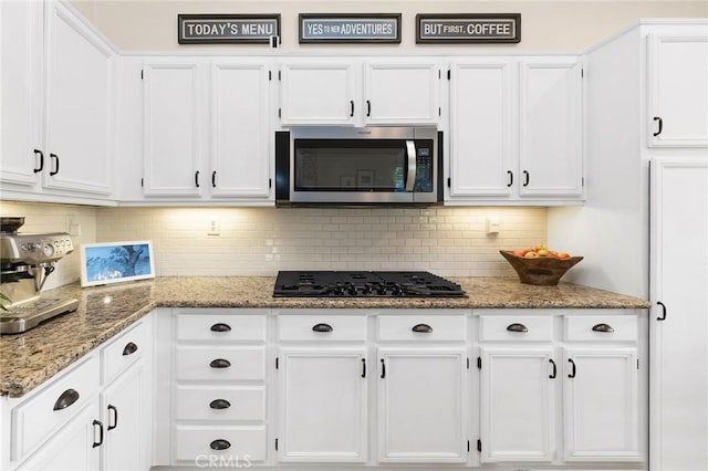 7476 Sequoia Ln, Highland, CA 92346 - kitchen featuring stainless steel microwave, white cabinetry, black gas cooktop, tasteful backsplash, and light stone countertops