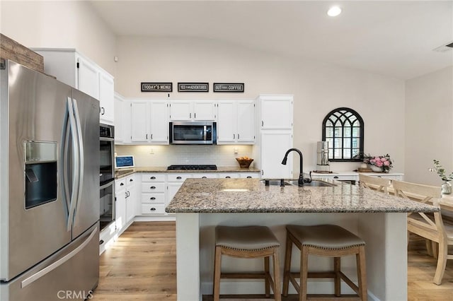 7476 Sequoia Ln, Highland, CA 92346 - kitchen with stainless steel appliances, a sink, lofted ceiling, light wood-type flooring, and white cabinetry
