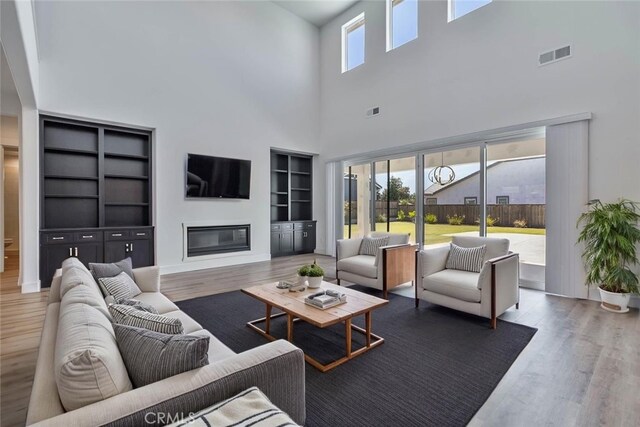 1734 Lester Ave, Clovis, CA 93619 - living room featuring wood finished floors, a glass covered fireplace, a high ceiling, and built in shelves