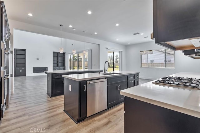 1734 Lester Ave, Clovis, CA 93619 - kitchen featuring a sink, stainless steel appliances, an island with sink, light wood-type flooring, and light countertops