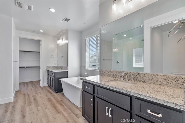 1734 Lester Ave, Clovis, CA 93619 - bathroom with tiled shower, two vanities, wood finished floors, a freestanding tub, and recessed lighting