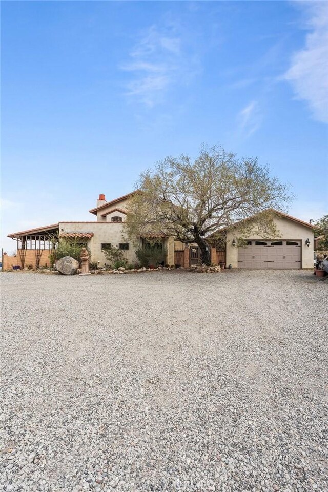 9075 Mesa Vista St, Apple Valley, CA 92308 - view of front of home featuring gravel driveway, an attached garage, and stucco siding