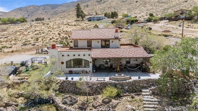 9075 Mesa Vista St, Apple Valley, CA 92308 - back of property with an outdoor fire pit, a patio area, a chimney, stucco siding, and a mountain view