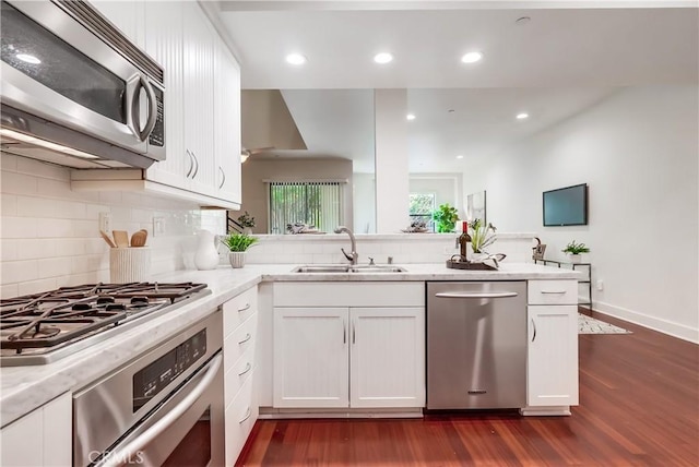 395 E 4th St Unit 13, Long Beach, CA 90802 - kitchen with appliances with stainless steel finishes, a sink, dark wood-style flooring, decorative backsplash, and white cabinetry