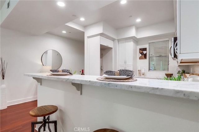 395 E 4th St Unit 13, Long Beach, CA 90802 - kitchen featuring a kitchen breakfast bar, white cabinetry, recessed lighting, dark wood-type flooring, and light stone countertops